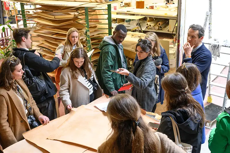 Notre Dame architecture students visiting the studios of Ateliers de France with old papers laid out on a table with students gathered around.