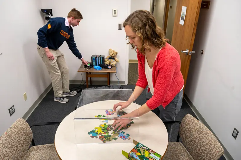 Katie Edler sets up a puzzle under a clear stand.