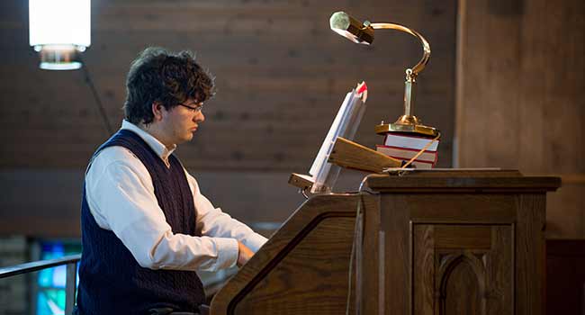 Jonathan Embry sitting at an organ