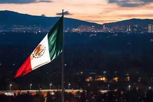 Mexican flag flies over Mexico City at dusk.