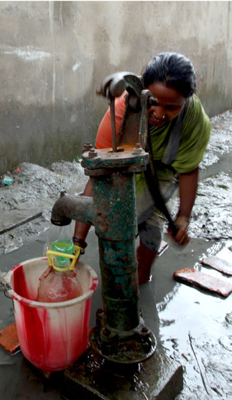 A woman pumps water into a bucket