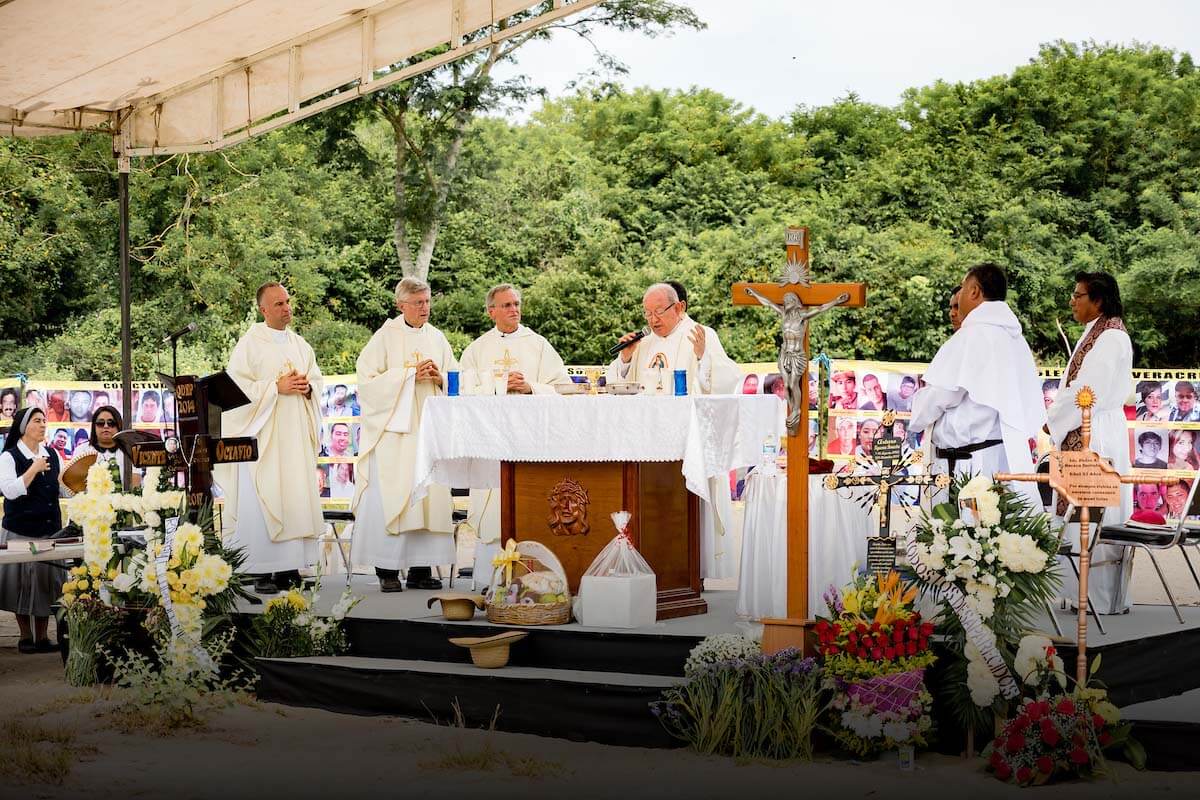 Father Jenkins at an alter with other religious. The alter is surrounded by colorful flowers.