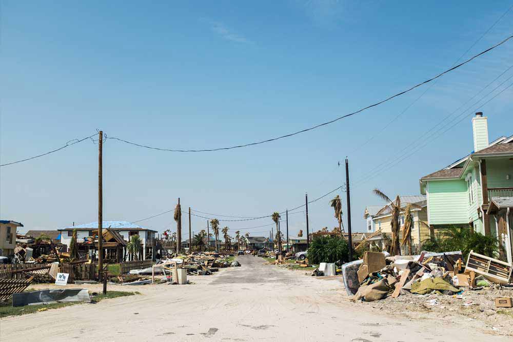 Piles of debris lays on both sides of a road.