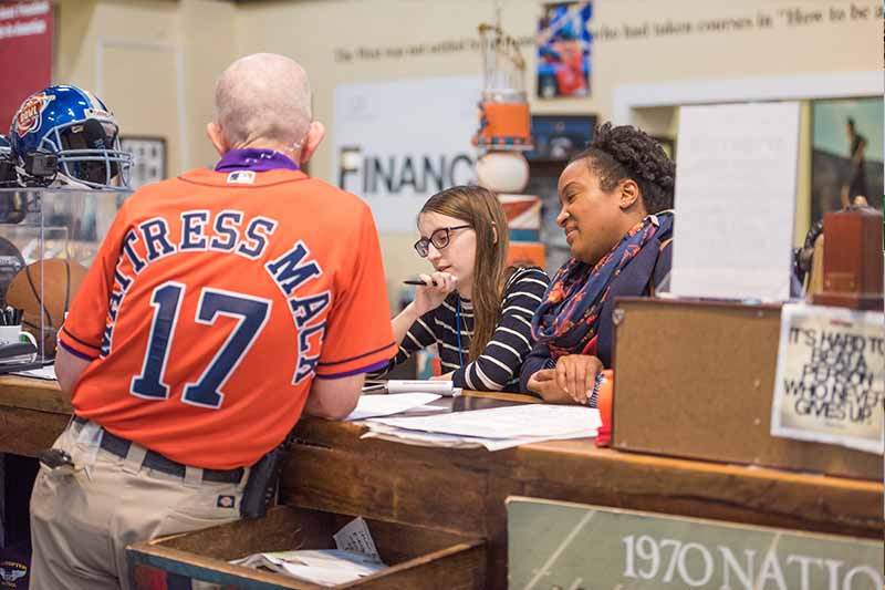 Student journalist Courtney Becker (center) and Prof. Victoria St. Martin interview Jim McIngvale.