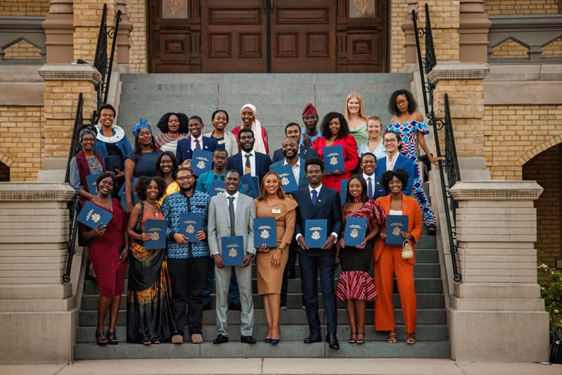 Students holding certificates on the steps of the Main Building