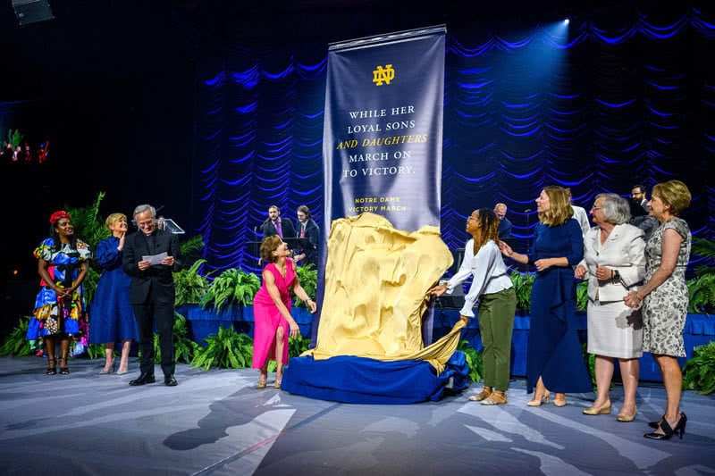 Revealing a banner on stage with on-stage members applauding.