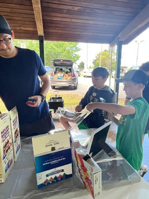 A man and two boys fill plastic bags with snacks.