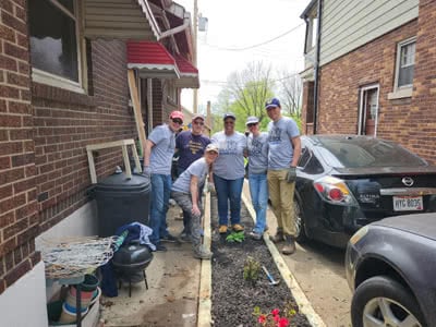 A group of people plants flowers in an alley.