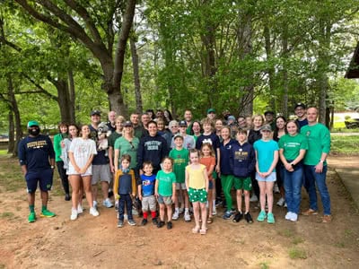 A group of volunteers pose for a picture in a wooded area.