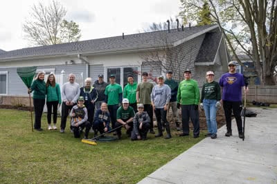 A group of volunteers pose in front of a house.