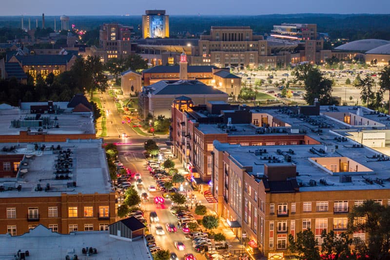 Eddy Street at dusk, shot from above with the Hesburgh Library and the Word of Life Mural—more commonly known as Touchdown Jesus—lit up in the background.