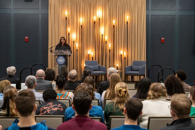 Natasha Thretheway stands at a podium giving a lecture for Walk the Walk Week.