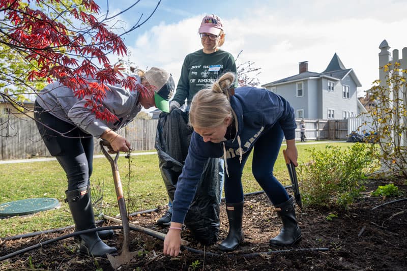 Three people raking leaves.