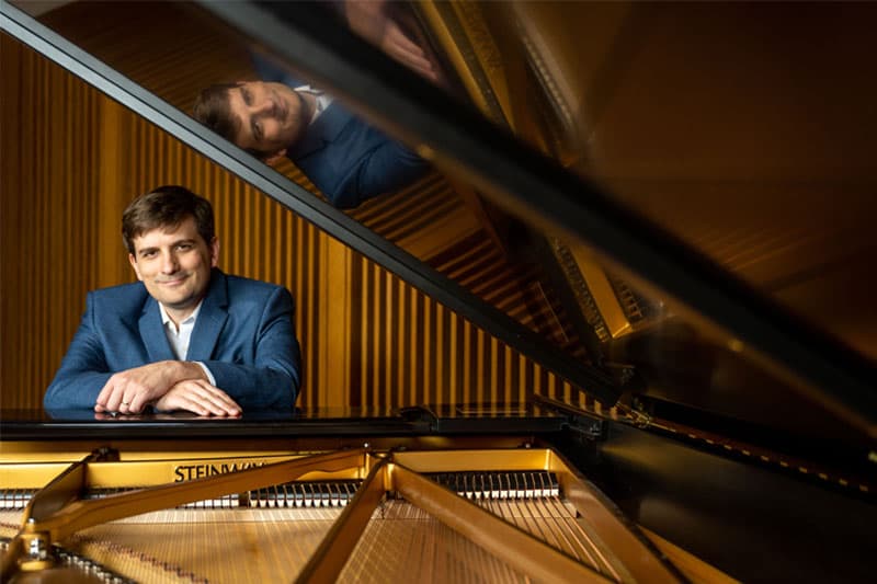 John Liberatore sits at an open grand piano.