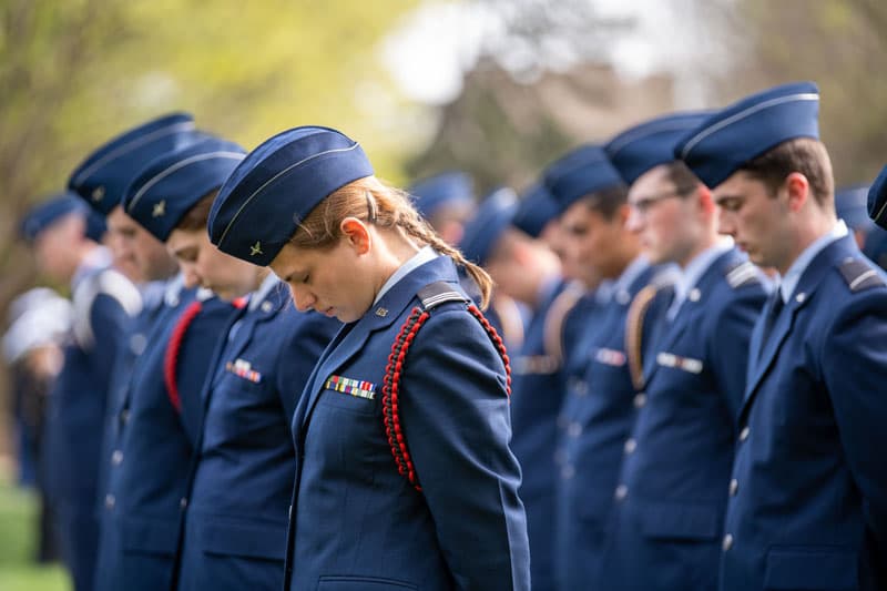 Students in their ROTC uniforms bowing their heads in reflection.