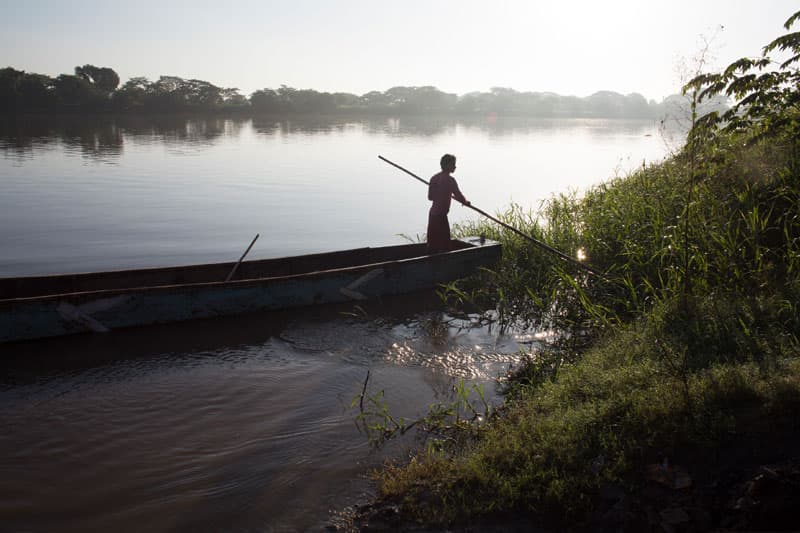 A person paddling in a canoe on a wide river.