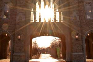 Sun shines through the archway of the Notre Dame Law School building.