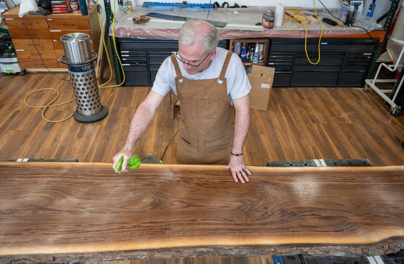 An overhead image of Fr. Dan Groody polishing a newly completed section of his table.
