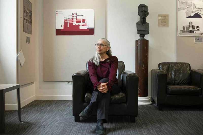 A woman sits on a leather chair looking off to the left.