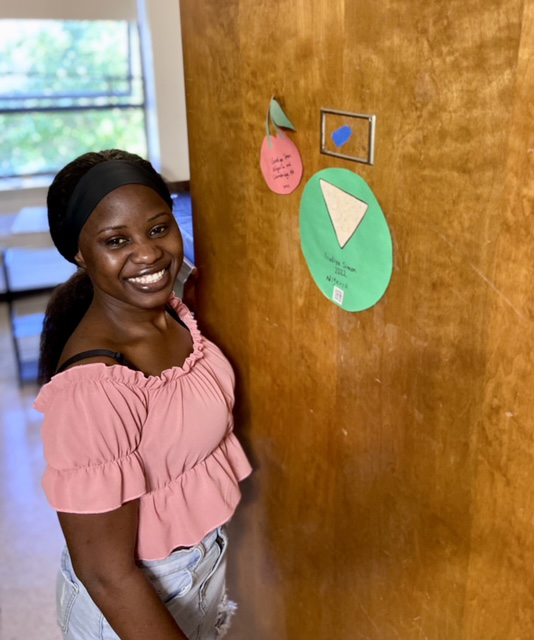 Godiya standing in front of a door to her dorm residence.