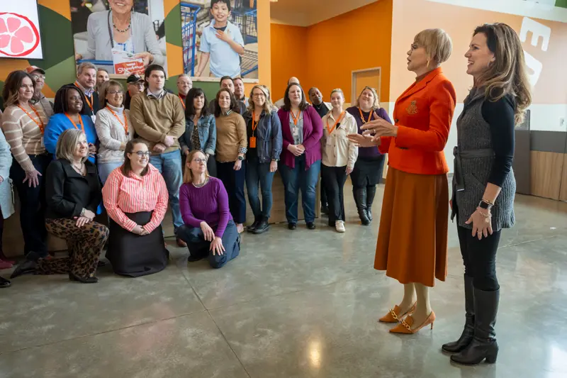 Claire Babineaux-Fontenot and Julie Yurko chat with volunteers before a group photo at the Northern Illinois Food Bank.