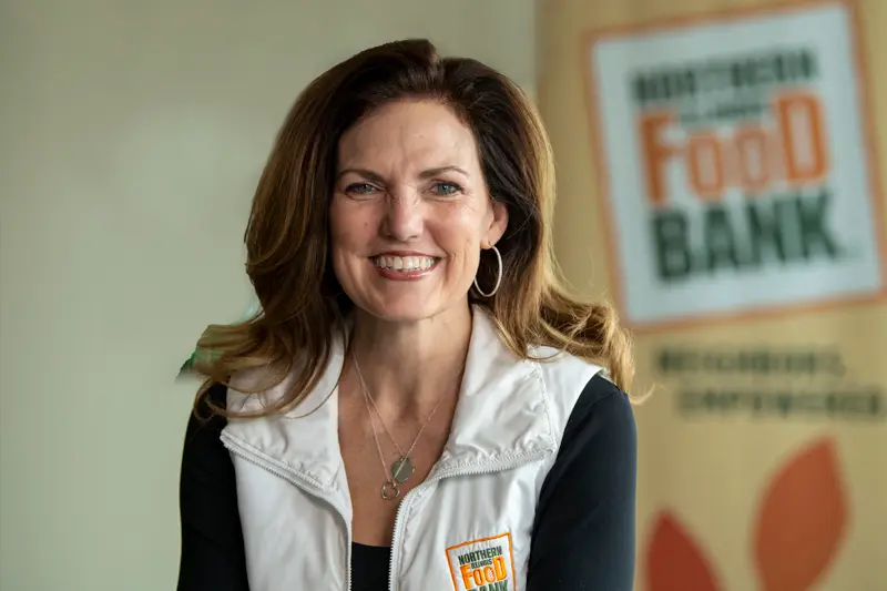 A portrait of Julie Yurko with a Feeding America sign behind her.