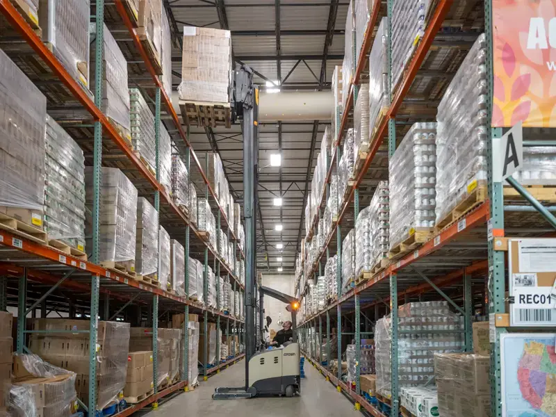 A person using a forklift to get pallets of food off the shelves at the Northern Illinois Food Bank.