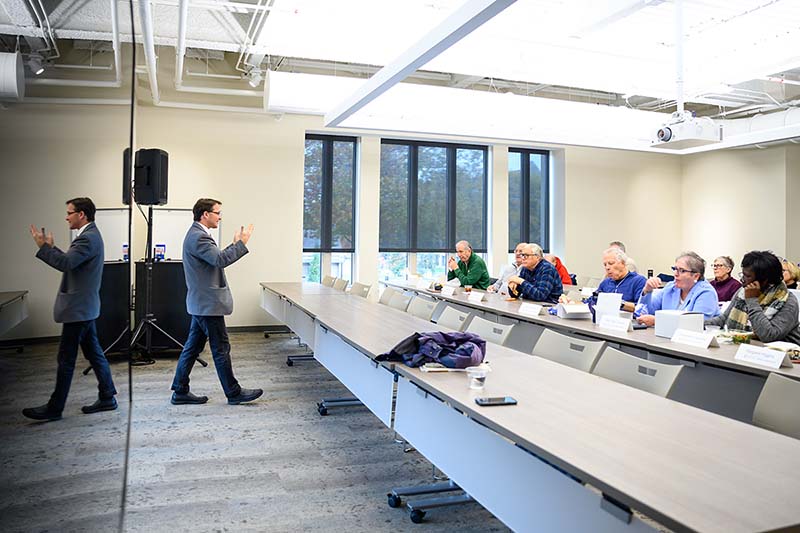 A speaker presents to a group of people in a classroom.