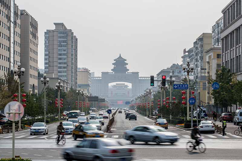 A busy road full of fast moving, blurred cars and bicyclists.