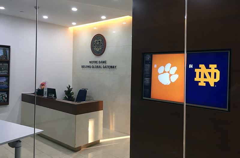 The Notre Dame Beijing Global Gateway lobby displays Clemson and Notre Dame's athletic logos on screen before entering.