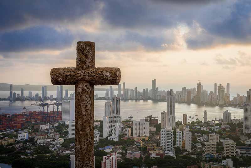 A cross looking over a bustling city.