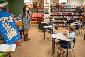 A masked teacher in front of a small group of ACE students.