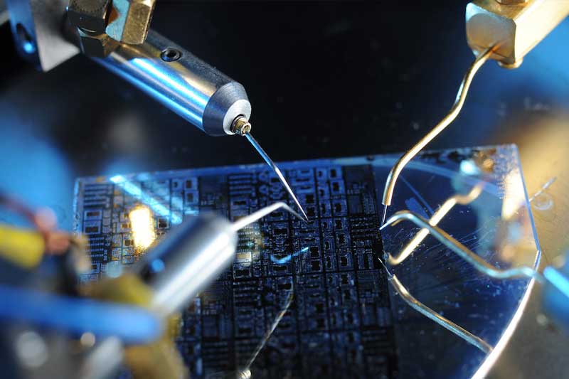 Metal devices work on a microchip in an engineering lab.