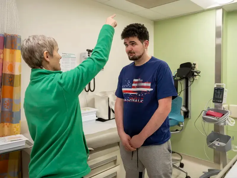 Dr. Elizabeth Berry-Kravis tests Alec Joujaians vision by standing in front of him and raising her arm. He follows the movement of her arm.