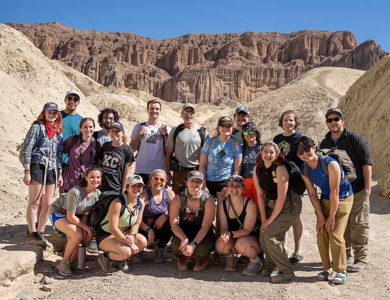 A group of students and their professor pose for a photo in the Golden Canyon badlands.