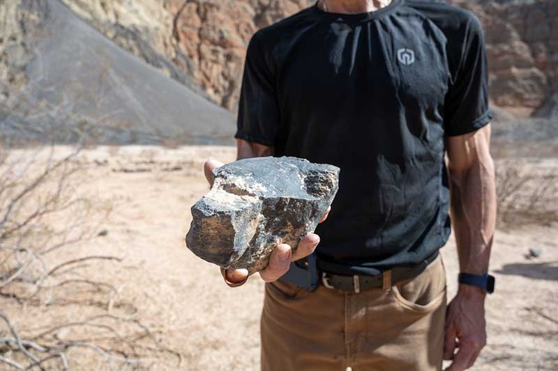A man holds a large piece of rock up to the camera.
