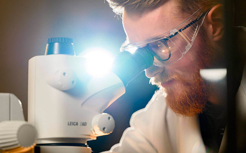 Image of a bearded man looking into a microscope.