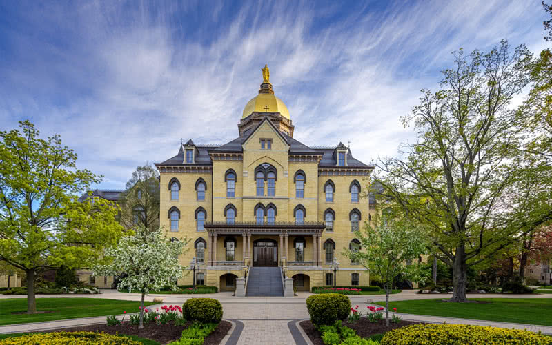 The Main Building of Notre Dame with the Golden Dome gleaming against a bright blue sky.