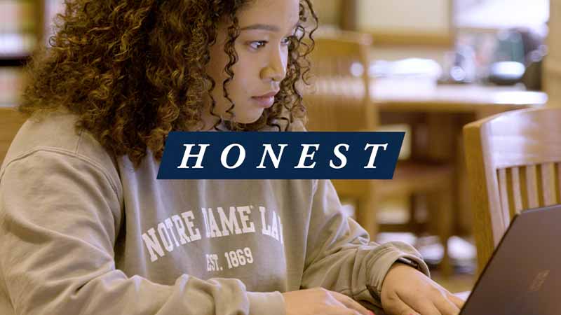 A Black woman works on her laptop. 'Honest text on top of the image.