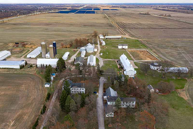 A large farm with solar panels in the background.