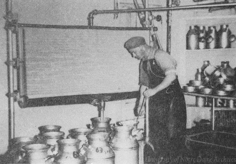 A man stands above several milk jugs, pasteurizing the milk.
