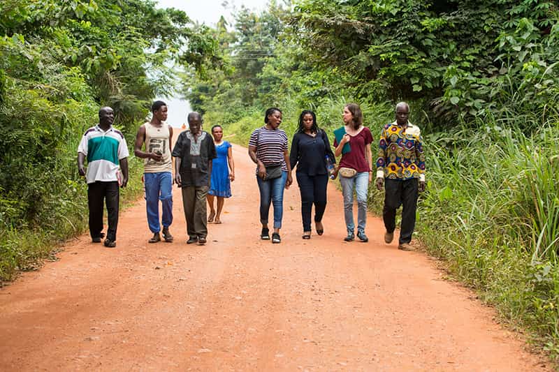 A group of people walk together down a dirt path.