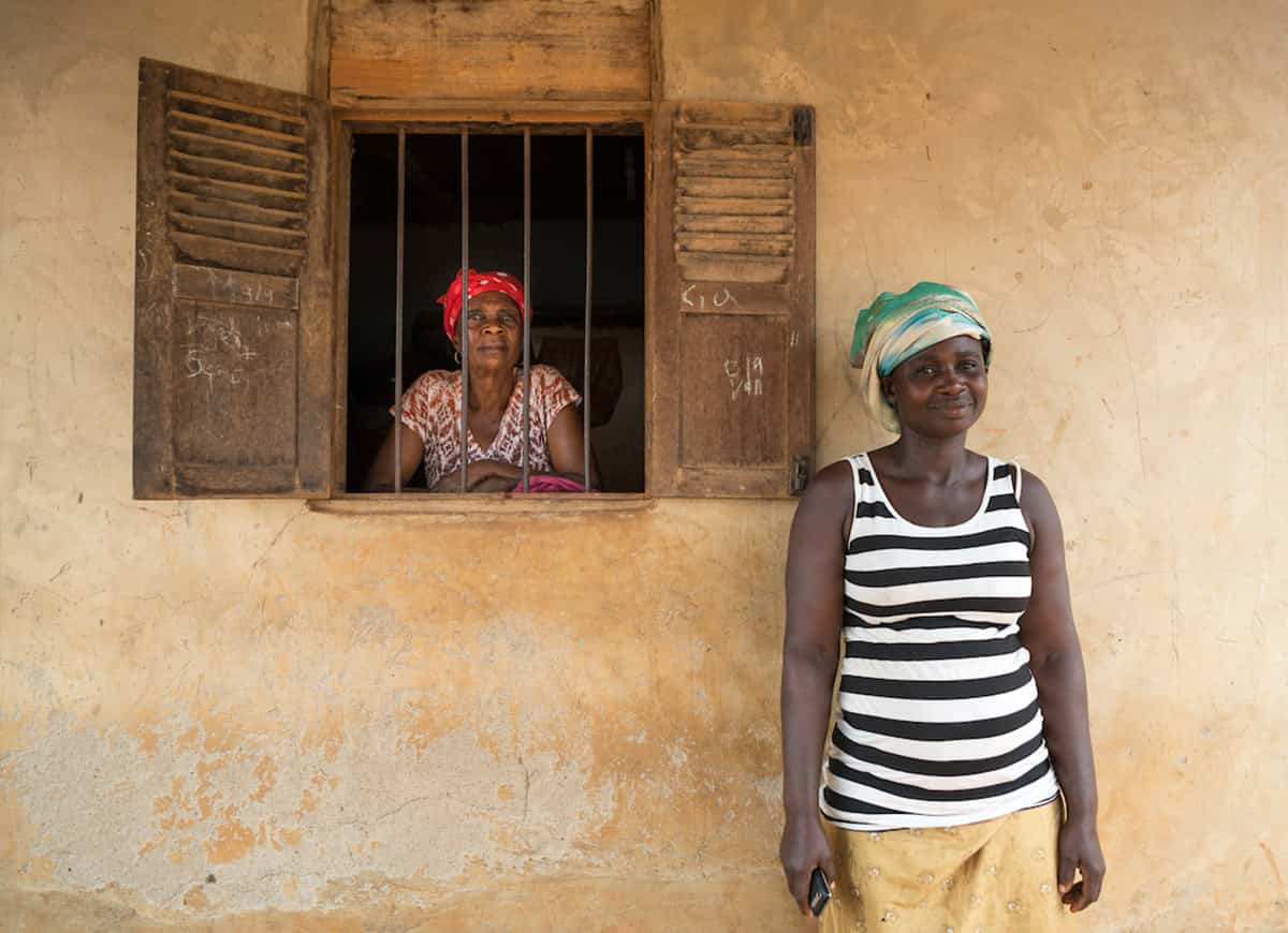 A mother and daughter pose for a photo outside of their home.