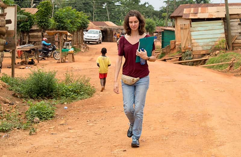 A woman walks down a dirt road.