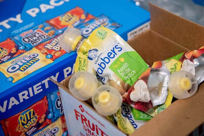 A variety pack of snacks and a box of baby food sit in the pantry.