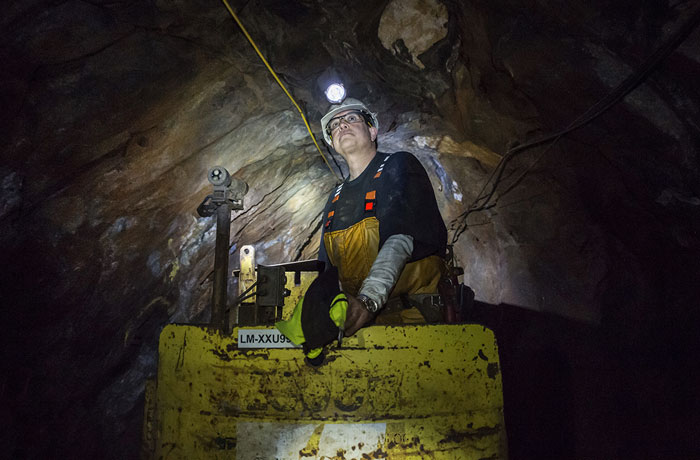 Infrastructure technician and former gold miner Mike Oates drives the train through a mine tunnel 4,850 feet below the surface.