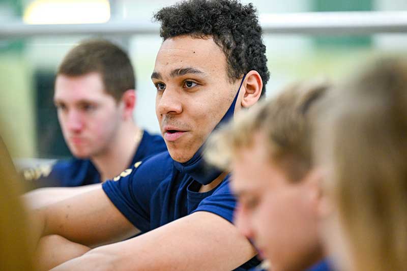 A student in focus speaks with middle schoolers that are blurred.