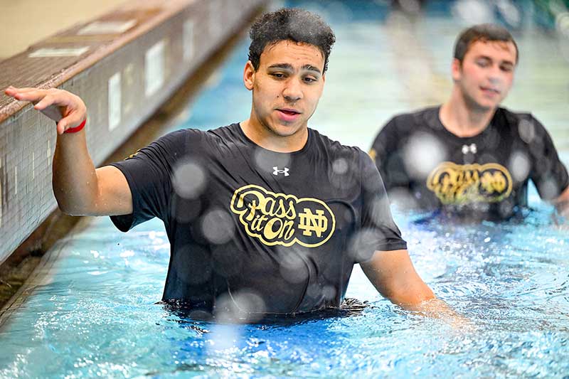 Two student athletes walk down a swim lane.