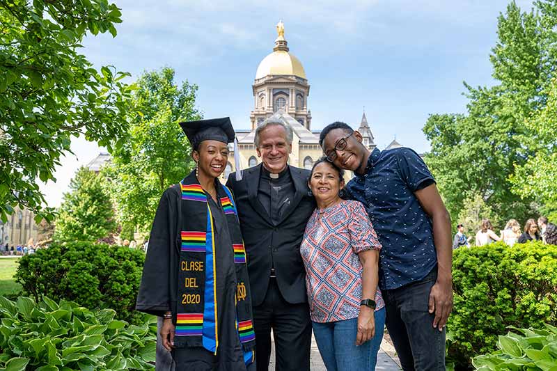 2020 Graduate Irla Atanda and her family pose for a photo with University of Notre Dame President Rev. John I. Jenkins, C.S.C. in front of the Main Building.