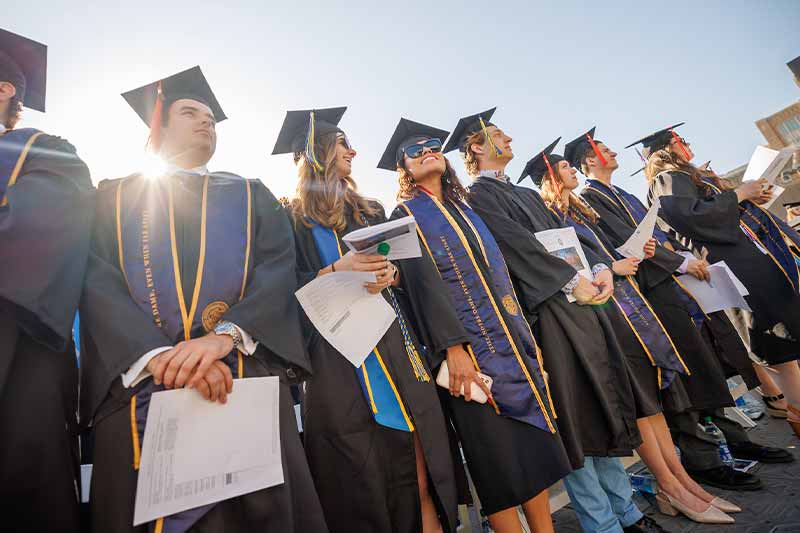 Graduates of the class of 2020 stand in the in Notre Dame Stadium.